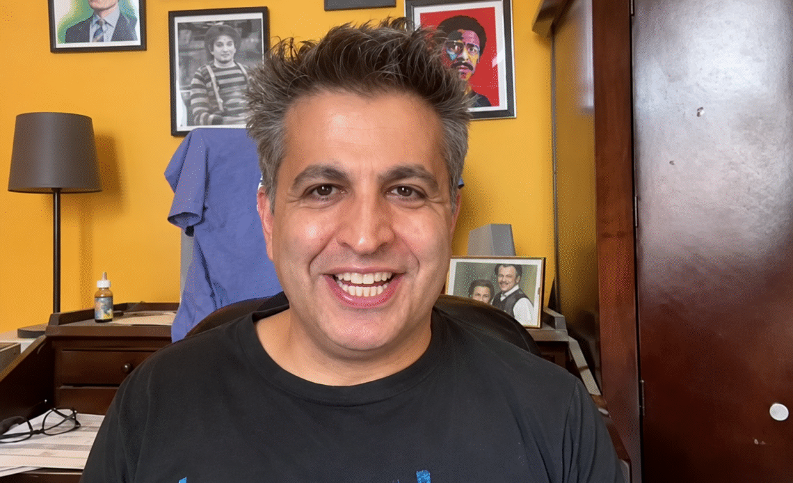 Paul Farahvar smiling in front of a wall of framed photos