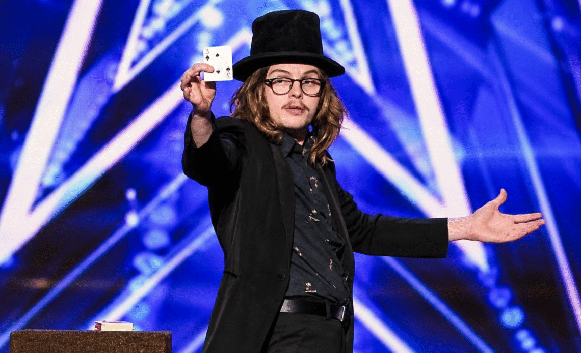 Jack Grady in a top hat performing a magic trick on the America's Got Talent stage