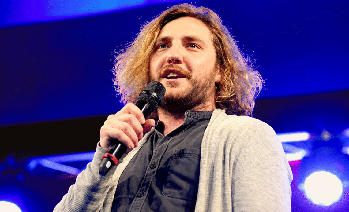 Seann Walsh performing stand-up under blue stage lights
