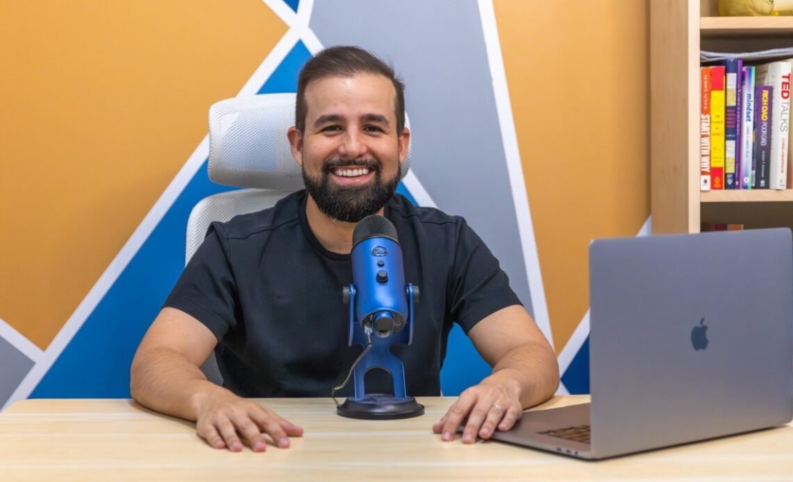 Stephan Dyer smiling at a desk with a microphone and laptop