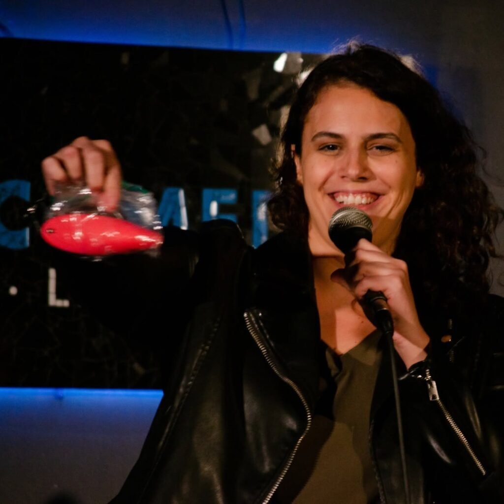 Jackie Joy smiling on stage with a microphone