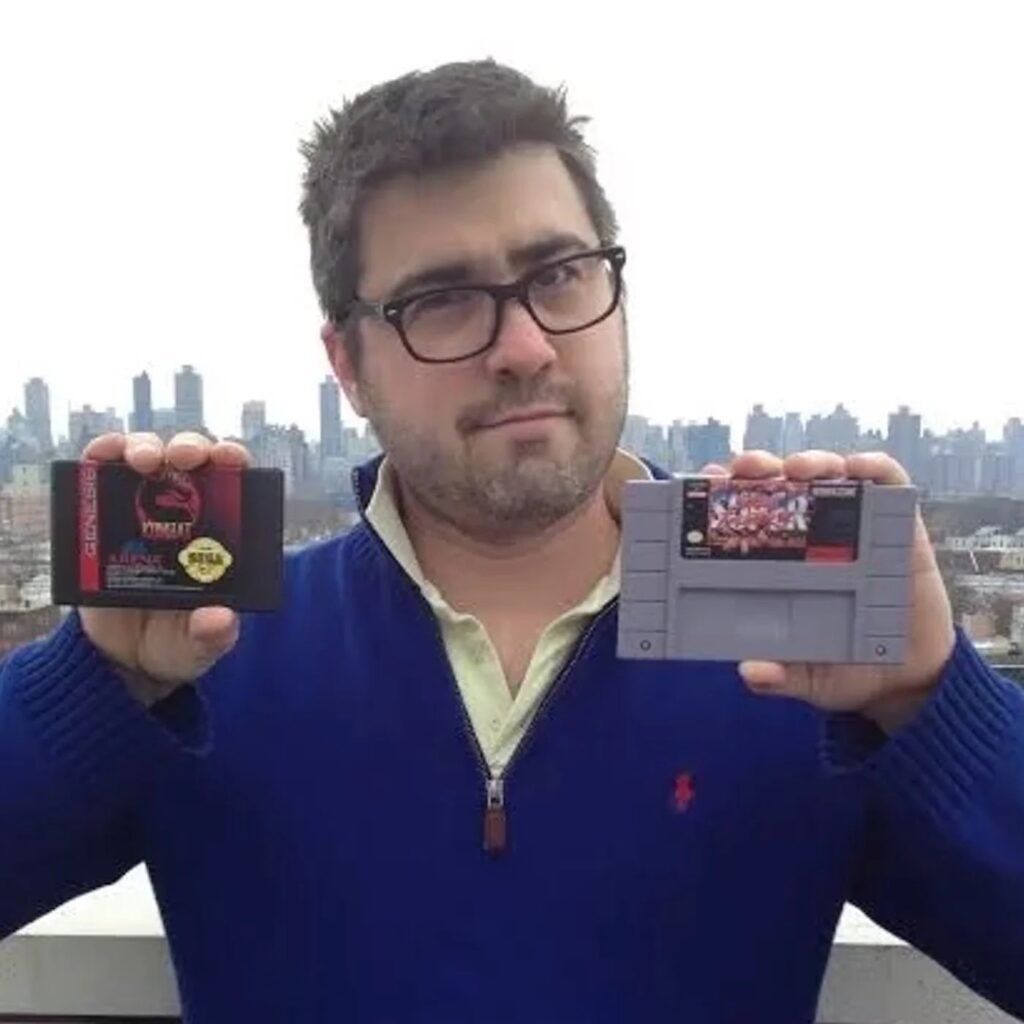 Blake J. Harris holding Sega and Nintendo game cartridges